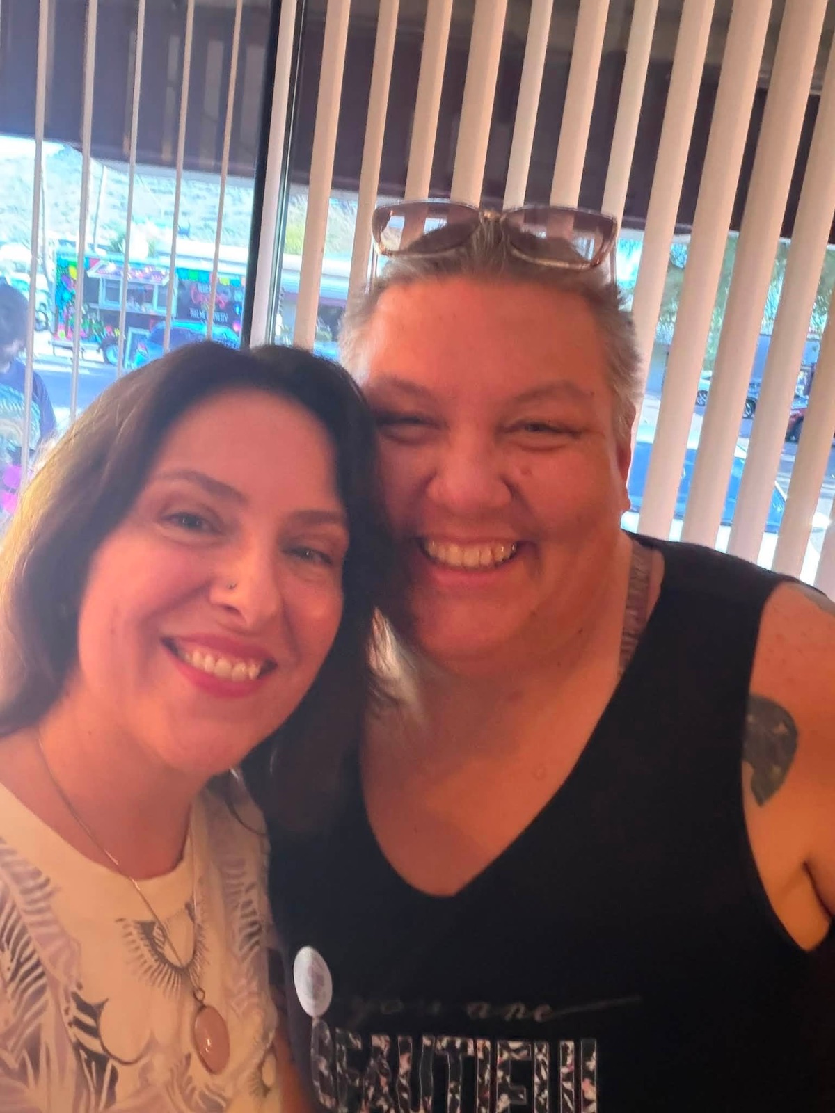 Two friends smiling for a close-up photo during the grand opening.